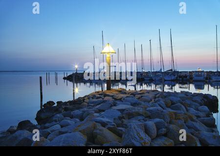 Port sur l'île de Poel. Bateaux à voile, phare et éclairage de lanterne à l'heure bleue. Paysage sur la côte de la mer Baltique Banque D'Images