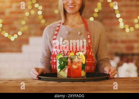 Young pretty woman with red and green cocktails on tray in the bar Stock Photo