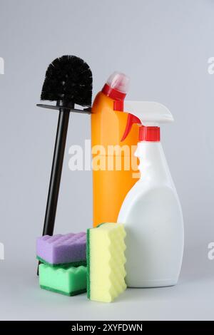 Différents nettoyants de toilette, éponges et brosse sur fond gris Banque D'Images