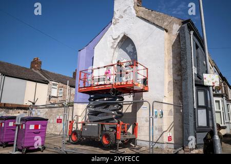 Kirkdale, Liverpool, Royaume-Uni, Flower Street Project 29 août 2024. Le projet Flower Streets est une célébration de Kirkdale et de ses résidents, et a déjà donné lieu à neuf peintures murales à grande échelle sur le côté pignon des maisons – chacune représentant les fleurs homonymes de chaque rue. Les œuvres d’art sont une célébration de la communauté et visent à rajeunir la région, ainsi qu’à aborder la question des comportements antisociaux. Et maintenant, deux autres œuvres incroyables vont être ajoutées à la collection. L’artiste visuelle Madeleine pires – qui a été responsable de toutes les œuvres à ce jour est retournée à Kirkdale Banque D'Images