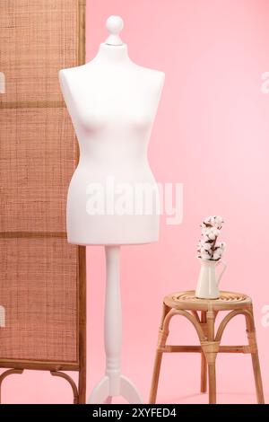 Mannequin féminin, écran pliant, tabouret et vase avec des fleurs de coton sur fond rose Banque D'Images