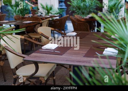 une salle à manger extérieure avec des tables et des chaises soigneusement agencées, entourée de plantes vertes luxuriantes Banque D'Images