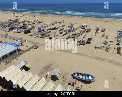Plage avec de nombreux bateaux, cabanes et parasols. En arrière-plan la mer et quelques visiteurs de plage, vue aérienne, bateaux de pêche étant tirés sur la plage, M Banque D'Images