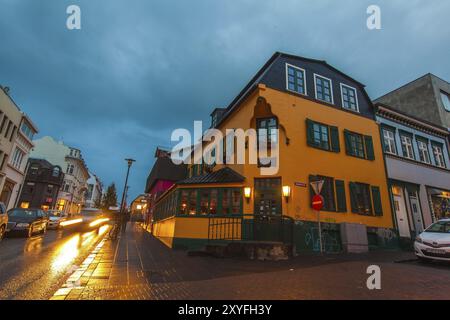 REYKJAVIK, ISLANDE, 06 JUILLET : le centre-ville la nuit avec des voitures garées sur une place devant un imposiing lumineux Buidling dans un quartier commerçant Banque D'Images