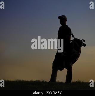 Male golfer jouer au golf au coucher du soleil Banque D'Images