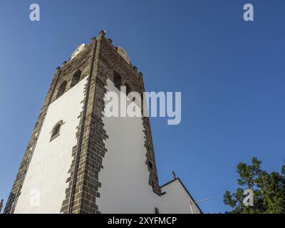 Grande tour d'église avec des horloges dans un bâtiment peint en blanc contre un ciel bleu clair, Funchal, madère, portugal Banque D'Images