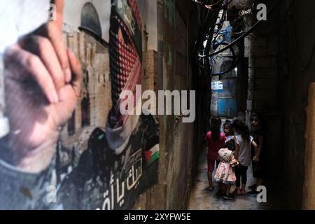Beyrouth, Liban. 29 août 2024. Enfants dans une rue du camp de réfugiés de Shatila aka Chatila avec affiche d'un combattant palestinien sur le mur. (Crédit image : © David Allignon/ZUMA Press Wire) USAGE ÉDITORIAL SEULEMENT! Non destiné à UN USAGE commercial ! Banque D'Images