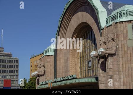 Un bâtiment historique de la gare ferroviaire avec des sculptures frappantes tenant des lampes contre un ciel dégagé, Helsinki, Finlande, Europe Banque D'Images