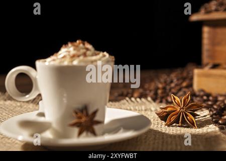 Close-up de café tasse de crème fouettée et d'anis étoilé sur fond noir Banque D'Images