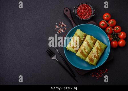 Crêpes aux épinards farcies au poulet, champignons, sel et épices sur fond de béton foncé Banque D'Images