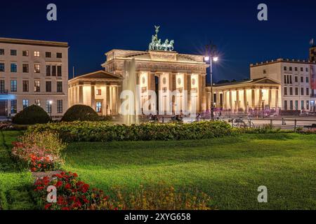 La célèbre porte de Brandebourg illuminée à Berlin avec une fontaine d'eau la nuit Banque D'Images