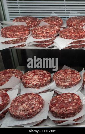 Patties hamburger empilées fraîchement préparées à vendre dans une boucherie. Banque D'Images