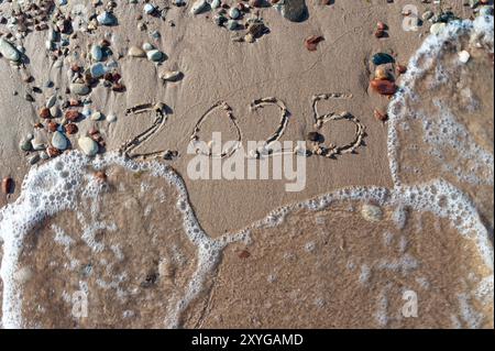 Message année 2024 remplacé par 2025 texte écrit sur fond de sable de plage. Au revoir 2024 bonjour à 2025 Happy New Year Coming concept. vue de dessus. Estonie Banque D'Images