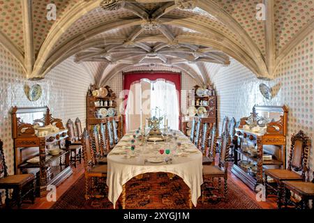 SINTRA, Portugal — la salle à manger du Palais de Pena, anciennement le réfectoire des moines Hiéronymites, convertie par le roi Ferdinand II en salle à manger privée de la famille royale portugaise. La chambre présente des voûtes en côtes manuélines datant du XVIe siècle et est bordée de tuiles du XIXe siècle réalisées par Fábrica Roseira. Le mobilier en chêne, commandé par le roi Ferdinand II en 1866 à Casa Barbosa e Costa, ajoute à l'ambiance historique et royale de l'espace. Banque D'Images