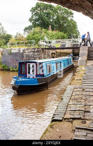 Bateau étroit quittant les écluses jumelles à double escalier sur le canal Shropshire Union à Bunbury Cheshire Banque D'Images