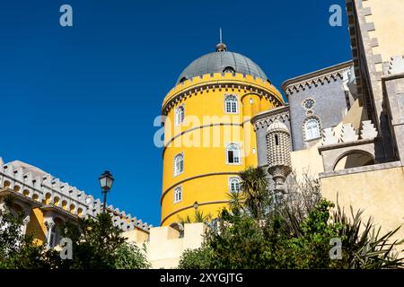 SINTRA, Portugal — L'architecture extérieure vibrante et éclectique du Palais de Pena, mettant en valeur son mélange de styles romantiste, mauresque et néo-manuélin. Les façades colorées du palais, les détails ornés et les éléments fantaisistes incarnent l'architecture romantique du XIXe siècle et la vision du roi Ferdinand II d'un château de conte de fées. Banque D'Images