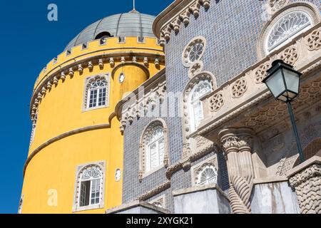 SINTRA, Portugal — L'architecture extérieure vibrante et éclectique du Palais de Pena, mettant en valeur son mélange de styles romantiste, mauresque et néo-manuélin. Les façades colorées du palais, les détails ornés et les éléments fantaisistes incarnent l'architecture romantique du XIXe siècle et la vision du roi Ferdinand II d'un château de conte de fées. Banque D'Images