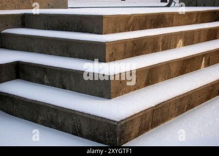 Les marches en béton sont légèrement recouvertes d’une couche de neige fraîche, créant un contraste serein entre la neige blanche froide et le ciment gris rugueux. Banque D'Images