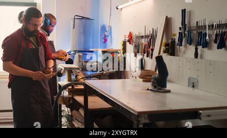 Menuisier utilisant un étau d'établi pour maintenir le bloc de bois, en commençant l'assemblage des meubles dans l'atelier. Artisan dans la menuiserie à l'aide de l'outil étau pour serrer le morceau de bois avant de le sculpter, caméra B. Banque D'Images