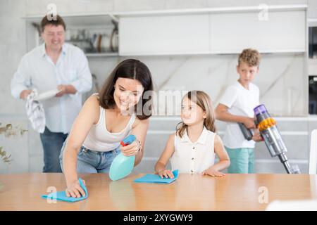 Famille heureuse avec deux enfants faisant le ménage dans la cuisine Banque D'Images