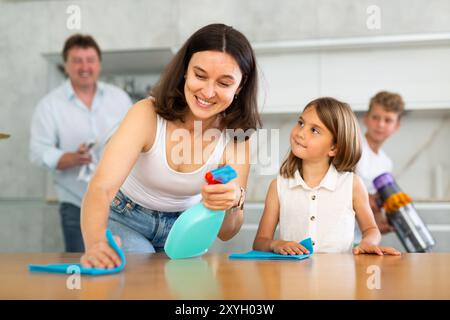 Famille heureuse avec deux enfants faisant le ménage dans la cuisine Banque D'Images