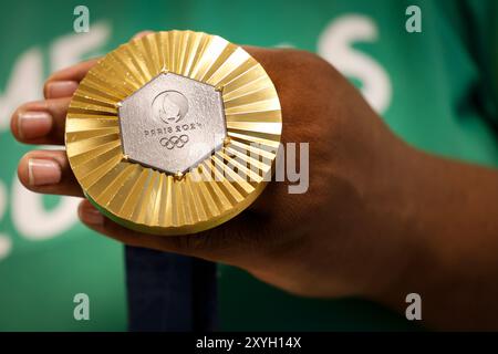 Médaille d'or des Jeux Olympiques de Paris 2024 prise de vue détaillée à la main, vainqueur d'une compétition sportive, symbole de réussite. Jeux olympiques d'été 2024 Banque D'Images