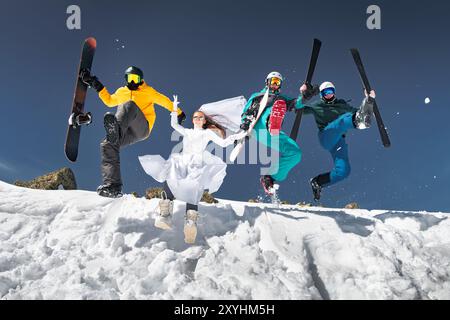 Groupe de jeunes amis heureux skieurs et snowboarders s'amusent et sautent de snowdrift. Concept de station de ski ou week-end d'hiver Banque D'Images