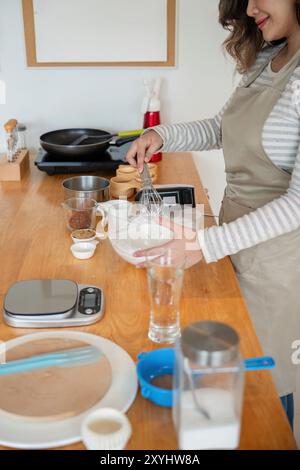 Femme asiatique fouettant avec confiance la pâte dans la cuisine moderne Banque D'Images