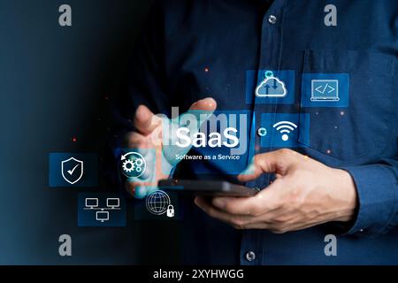 Concept SaaS, Software as a Service, Un smartphone MAN tape avec des icônes numériques représentant divers aspects du logiciel en tant que Service (SaaS), souligne Banque D'Images