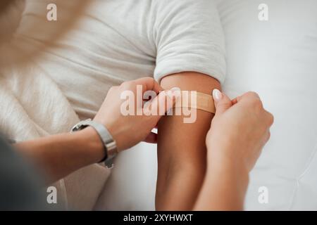 Mains, bras et femme avec bandage pour enfant dans la chambre à coucher à la maison pour le bien-être ou les soins de santé. La famille, les premiers soins et la mère appliquent le plâtre de bandaid sur mal ou Banque D'Images