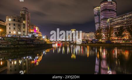 Lumières reflétées dans le canal du Danube, à gauche l'observatoire d'Urania, à droite les tours de bureaux illuminées, plan de nuit, Vienne, Autriche, Europe Banque D'Images