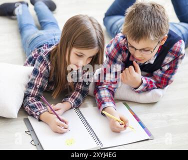 Frère et soeur le dessin avec des crayons de couleur dans la salle de séjour Banque D'Images