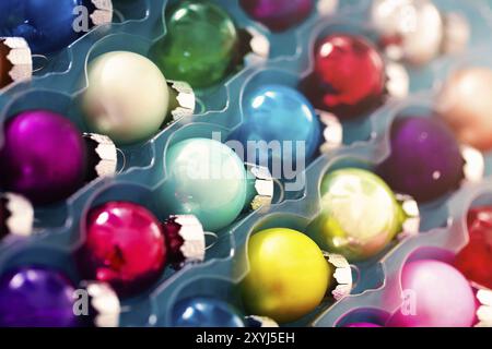 Gros plan composé de boules de Noël colorées à la décoration arrondie dans un récipient transparent en plastique Banque D'Images