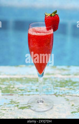 Verres de champagne à la fraise sur fond bleu turquoise. Cocktail Rossini. Summer pool party Banque D'Images