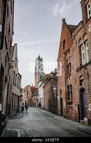 Une scène de rue classique avec des pavés et des maisons sur Oostmeers à Bruges, en Belgique, lors d'une soirée d'été lumineuse avec quelques personnes marchant sur le trottoir. Banque D'Images