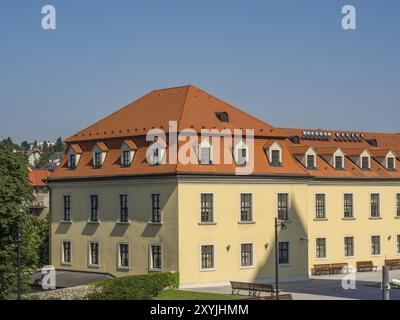 Vue d'un bâtiment jaune avec des toits rouges et de nombreuses fenêtres sous un ciel bleu clair, bratislava, slovaquie Banque D'Images