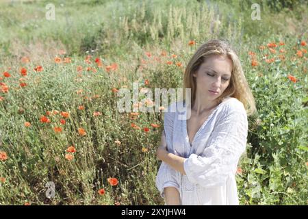 Belle fille blonde dans le champ de coquelicots Banque D'Images