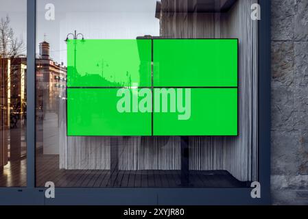 Quatre téléviseurs à écran large avec maquettes d'écran vert pour les bannières et la marque. Vitrine vide avec panneaux publicitaires vierges Banque D'Images