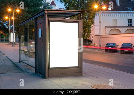 Maquette du panneau d'affichage d'arrêt de bus avec toilettes publiques intégrées sur le trottoir de la rue. Visionneuse pour affiches publicitaires extérieures la nuit Banque D'Images