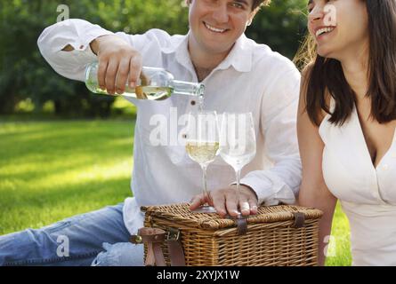 Jeune couple heureux appréciant un verre de vin blanc dans le jardin Banque D'Images
