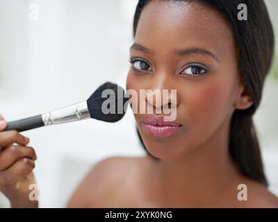 Femme noire, pinceau de maquillage et portrait avec beauté à la maison, fond de teint et application de blush avec confiance. Fille, produit cosmétique et lueur de soi Banque D'Images