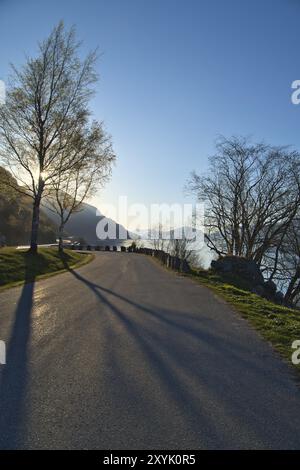 Parking donnant sur la route, le Nordfjord et Bergen en Norvège. Les rayons du soleil tombent à travers les arbres. Paysage de Scandinavie Banque D'Images