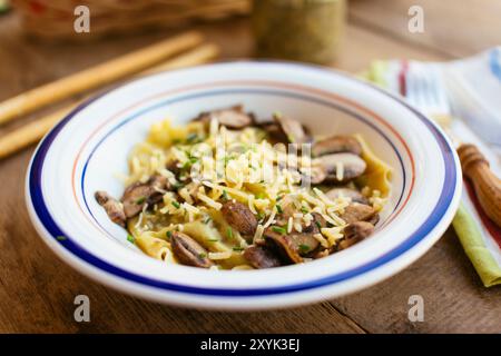 Raviolis faits maison au chou frisé et au pesto aux noix avec champignons et fromage végétalien râpé saupoudré et garni de ciboulette. Banque D'Images