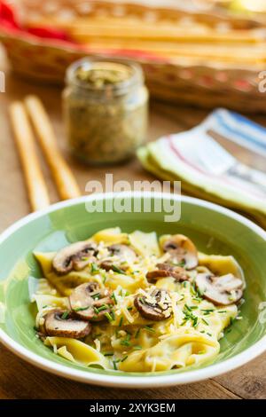 Raviolis faits maison au chou frisé et au pesto aux noix avec champignons et fromage végétalien râpé saupoudré et garni de ciboulette. Banque D'Images