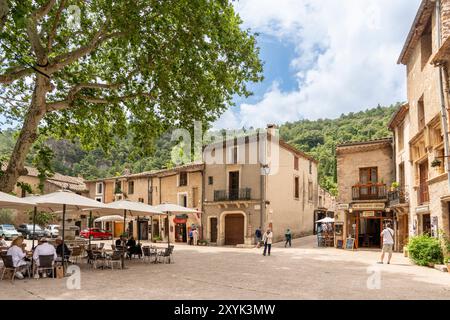 Les gens au café en plein air sur la place du village de la liberté, St Guilhem le désert, Hérault, Occitanie, France, Europe Banque D'Images