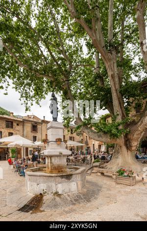 Les gens au café en plein air sur la place du village de la liberté, St Guilhem le désert, Hérault, Occitanie, France, Europe Banque D'Images