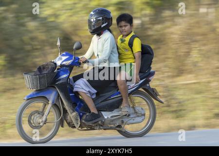 Mère avec son fils en uniforme scolaire sur une moto, Vang Vieng, province de Vientiane, Laos, Asie Banque D'Images