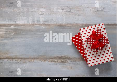 Boîtes cadeaux enveloppées dans du papier polkadots et coeurs avec ruban sur fond de bois bleu, style rétro vintage Banque D'Images