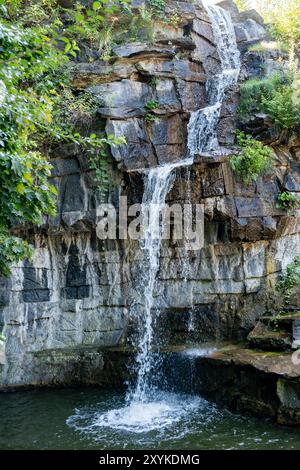 Une chute d'eau descend d'une falaise rocheuse. L'eau est claire, les pierres sont grises. La scène est paisible et sereine. Banque D'Images