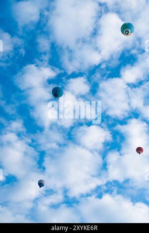 Montgolfière volant entre les nuages dans le ciel bleu. photo ci-dessous. Banque D'Images